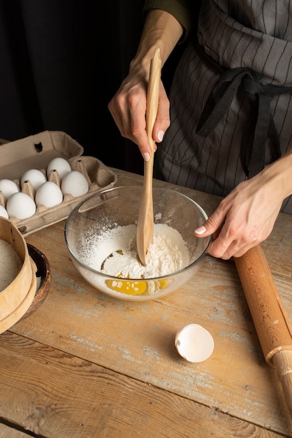 Foto grátis feche a mão misturando farinha e ovo