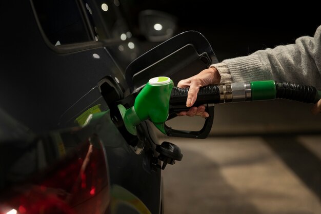 Feche a mão segurando a bomba de gasolina