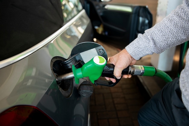 Feche a mão segurando a bomba de gasolina