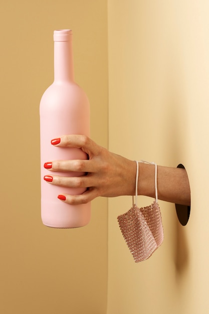 Feche a mão segurando a garrafa rosa