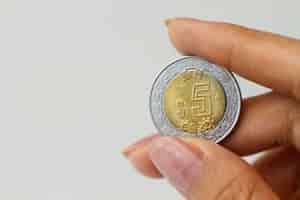 Foto grátis feche a mão segurando a moeda mexicana