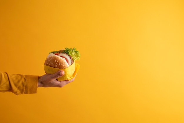 Feche a mão segurando um hambúrguer saboroso