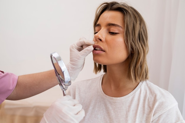 Feche a mulher olhando no espelho após o preenchimento labial