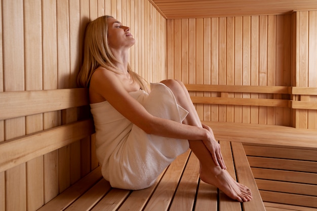 Feche a mulher relaxando na sauna