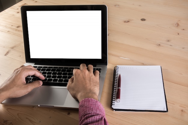 Feche acima da mão do homem de negócios que trabalha no portátil com o caderno na tabela. Conceito de trabalho empresarial.