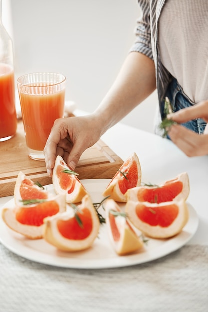 Feche acima da menina que decora a placa com toranja e alecrim cortados. Conceito de nutrição fitness. Copie o espaço.