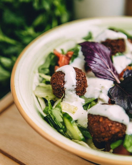 Feche acima da metade da salada de almôndega, guarnecida com molho de iogurte