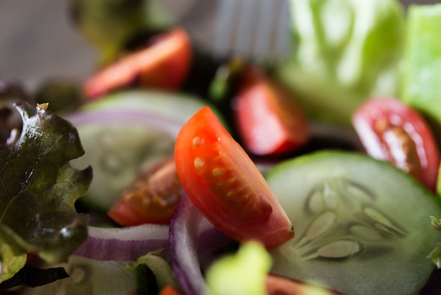 Feche acima da salada dos legumes frescos na bacia com fundo de madeira velho rústico. Conceito de alimentos saudáveis.