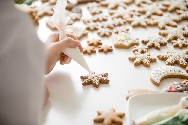 Feche acima das mãos de confeiteiras femininas, gengibre, estrelas de gengibre