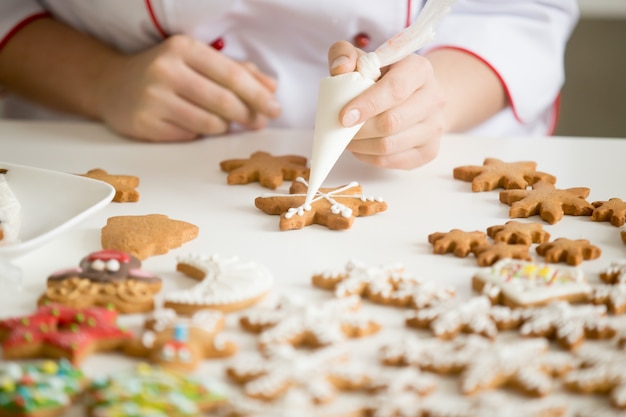 Feche acima das mãos de confeiteiras femininas que decoram estrelas