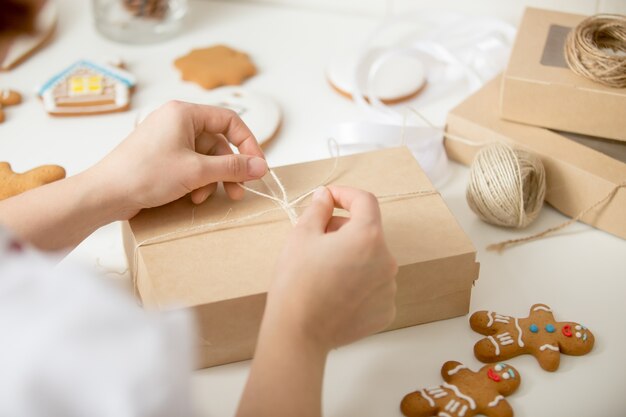 Feche acima das mãos de confeiteiro envolvendo uma caixa de papelão