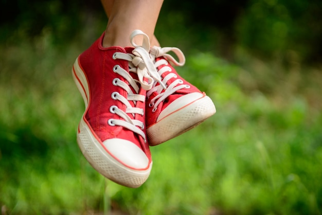 Foto grátis feche acima das pernas da menina em keds vermelhos na grama.