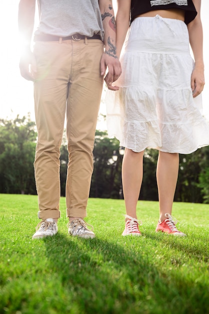 Feche acima das pernas do casal em keds na grama.