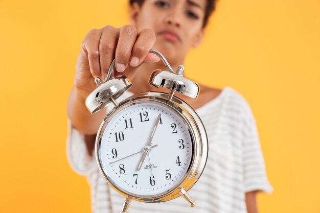 Feche acima do despertador na mão da mulher isolada