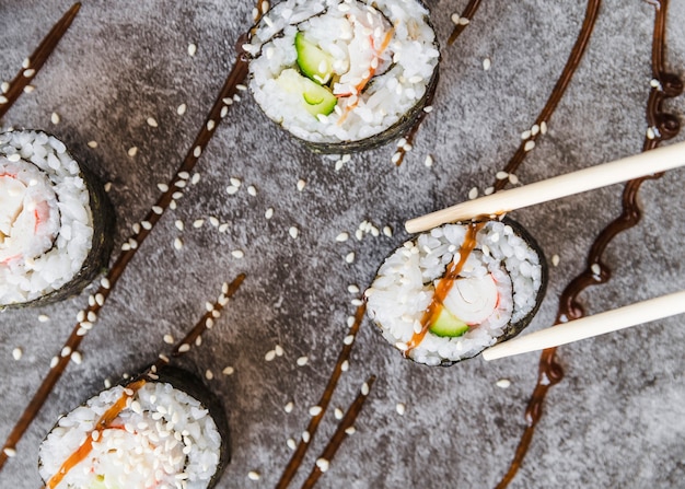 Foto grátis feche acima dos chopsticks do tiro que pegaram o rolo de sushi