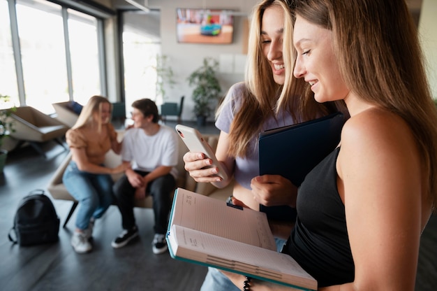 Feche amigos com livro e smartphone