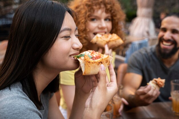 Feche amigos sorridentes comendo pizza