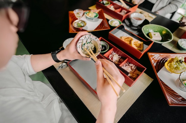 Foto grátis feche as mãos comendo com pauzinhos