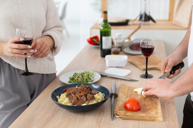 Feche as mãos cortando comida com uma faca