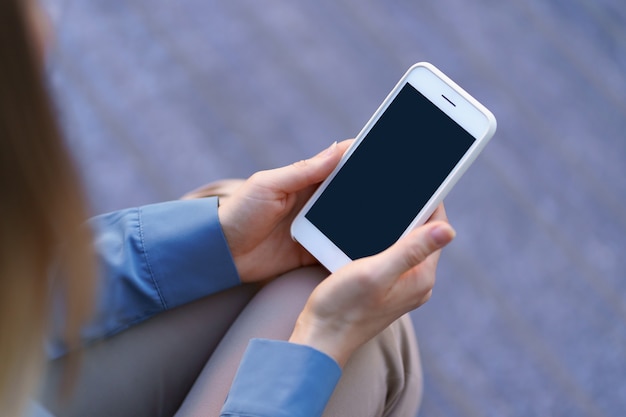 Feche as mãos de uma mulher segurando um smartphone com tela preta