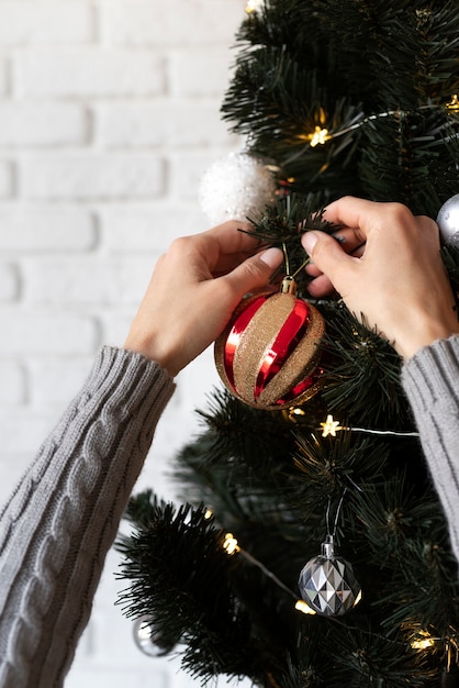 Feche as mãos decorando a árvore