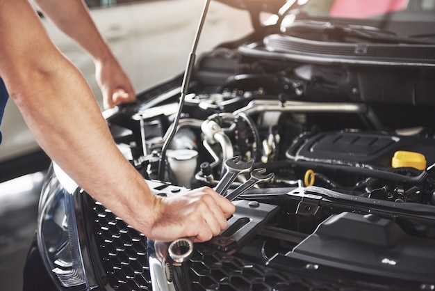 Feche as mãos do mecânico irreconhecível, fazendo serviço e manutenção do carro.