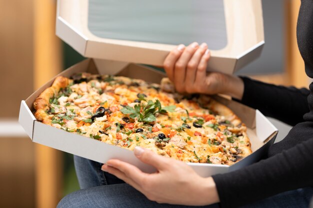Feche as mãos segurando caixas de pizza