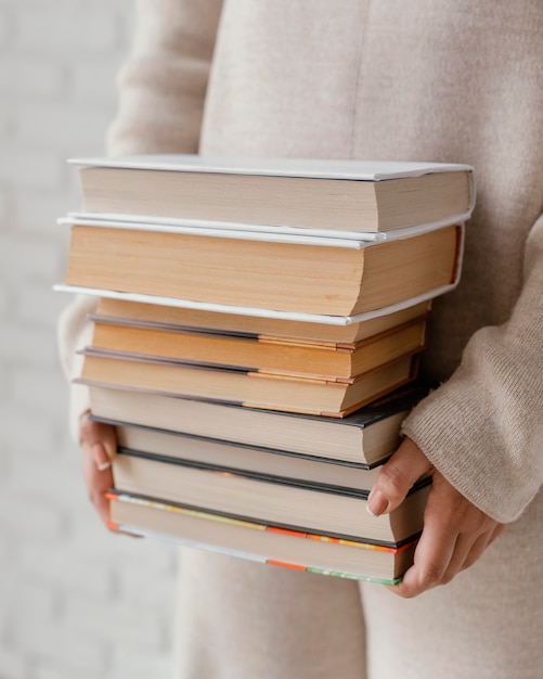 Feche as mãos segurando uma pilha de livros