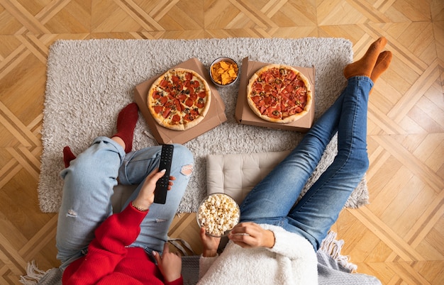 Feche as mulheres com pipoca e pizza