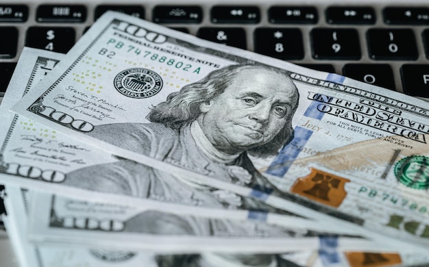Feche as notas de dólar no conceito de fazer dinheiro para laptop