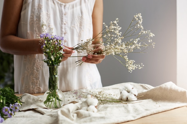 Feche de jovem florista feminina trabalhando com ramo de flores no local de trabalho.