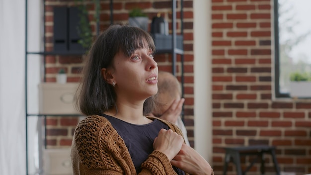 Feche de mulher chorando e compartilhando história sobre dependência de álcool na terapia de grupo. Adulto tendo uma reação triste sobre problemas de saúde mental na frente de pessoas em uma reunião de reabilitação.