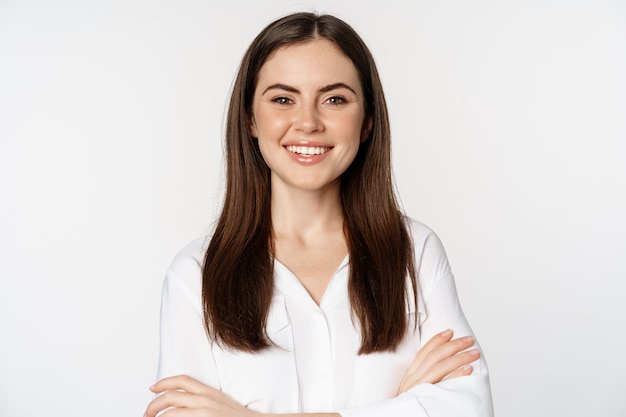 Feche de mulher corporativa confiante, empresário profissional sorrindo, cruzando os braços no peito e sorrindo entusiasmado, de pé sobre fundo branco.