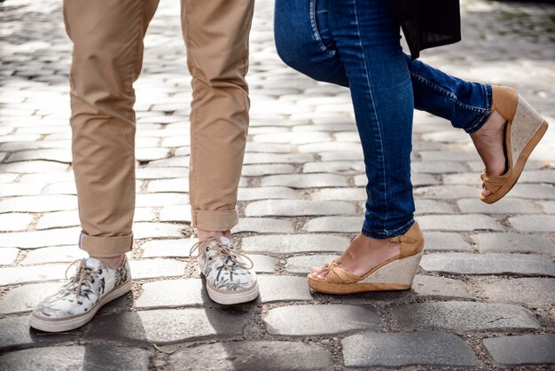 Feche de pernas do casal em keds em pé na rua.