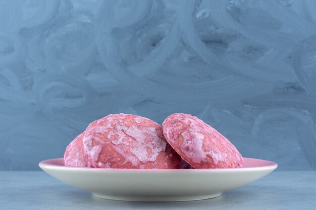 Feche deliciosos biscoitos de foto rosa no prato cinza.