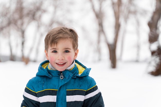 Feche e uma criança feliz brincando na neve