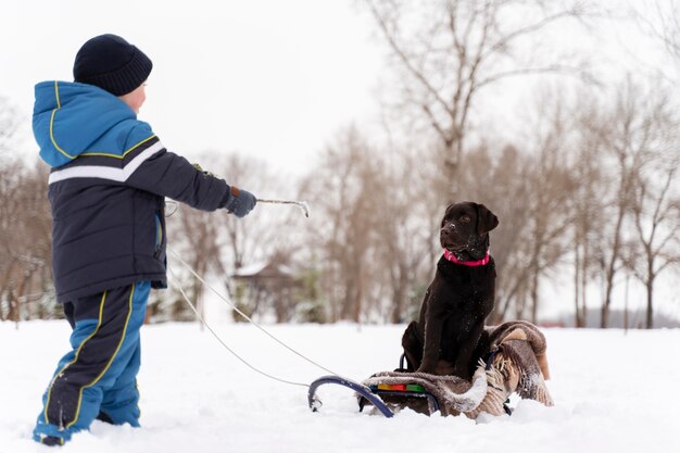 Feche e uma criança feliz brincando na neve