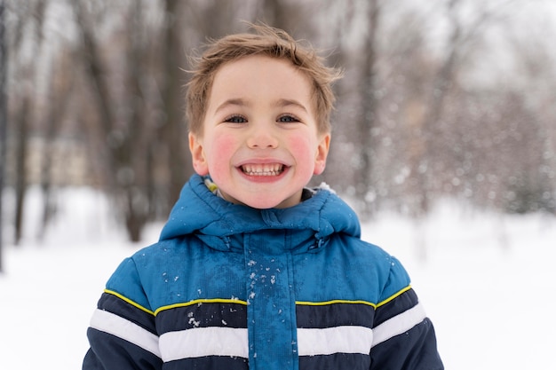Feche e uma criança feliz brincando na neve