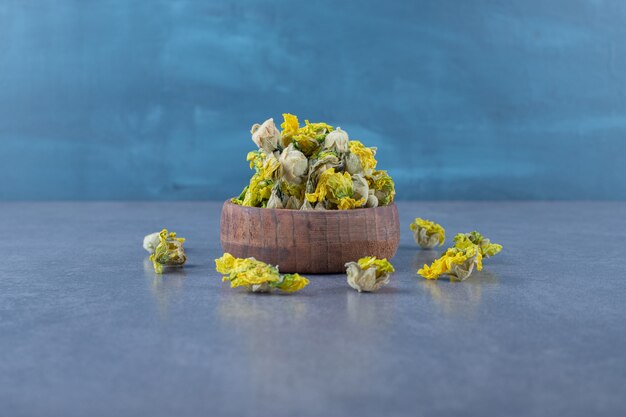 Feche foto de flores secas em uma tigela de madeira sobre cinza.