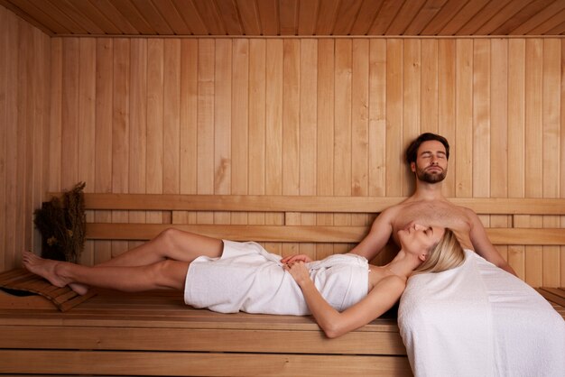 Feche o casal relaxando na sauna