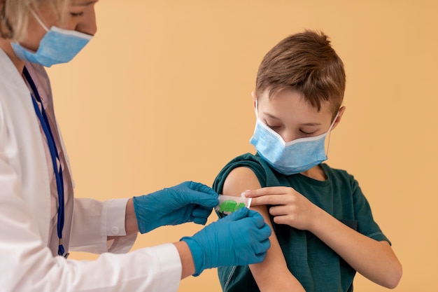 Feche o garoto e o médico usando máscaras