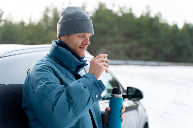 Feche o homem desfrutando de bebida quente durante a viagem de inverno