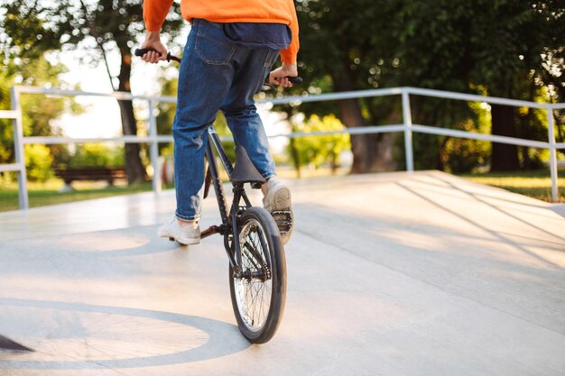 Feche o jovem andando de bicicleta no skatepark moderno isolado