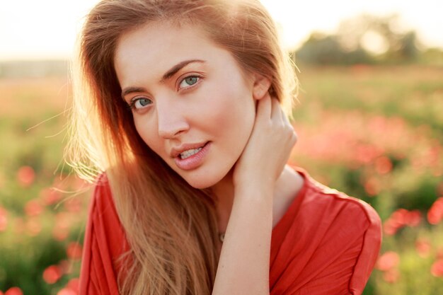 Feche o retrato da beleza da mulher sedutora com a pele perfeita, posando no campo ensolarado.