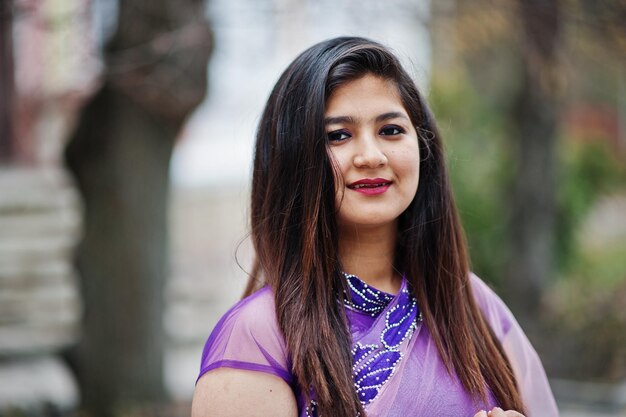 Feche o retrato da garota hindu indiana no tradicional saree violeta posado na rua