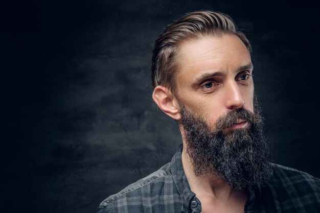 Feche o retrato de homem barbudo com cabelo comprido sobre fundo escuro.