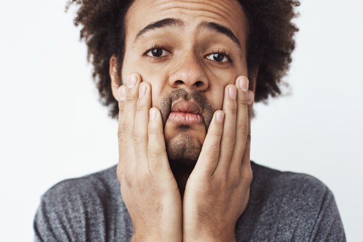 Foto grátis feche o retrato de jovem africano chateado e cansado, agarrando seu rosto e bochechas com as mãos. estudante trabalhador no final do dia ou vítima de um acidente de carro sem seguro