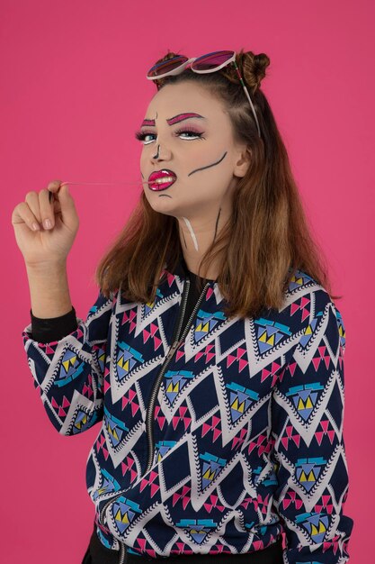 Feche o retrato de jovem usando maquiagem criativa e olhando para a câmera enquanto masca chiclete. Foto de alta qualidade