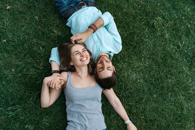 Feche o retrato de um casal despreocupado deitado na grama juntos e apaixonados