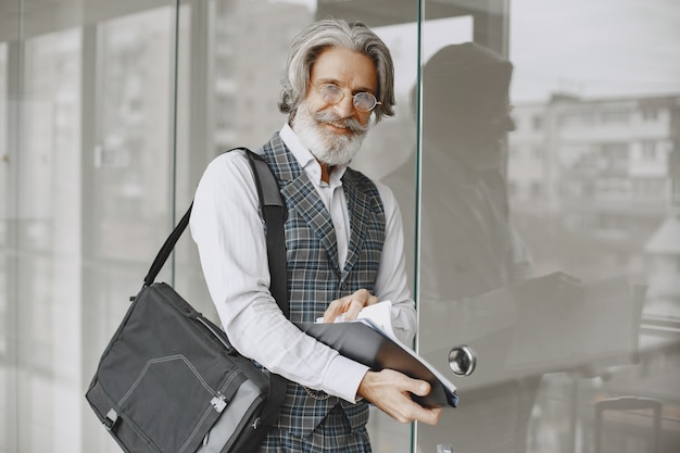 Feche o retrato de um homem antiquado sorridente. Homem elegante no escritório. Sênior com documentos.